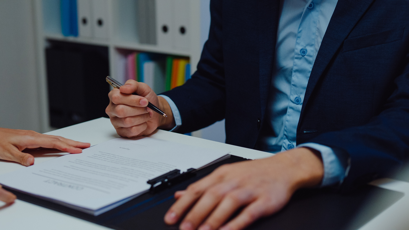 Closeup of young asian businessman mentor corporate leader manager counselor communicate with businesswoman and sign a contract at office night. businesspeople in workplace.