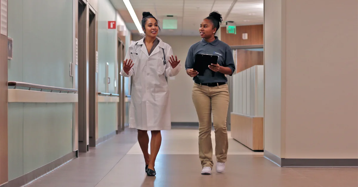 Care Navigator Scholar walking with a healthcare professional in a hospital hallway