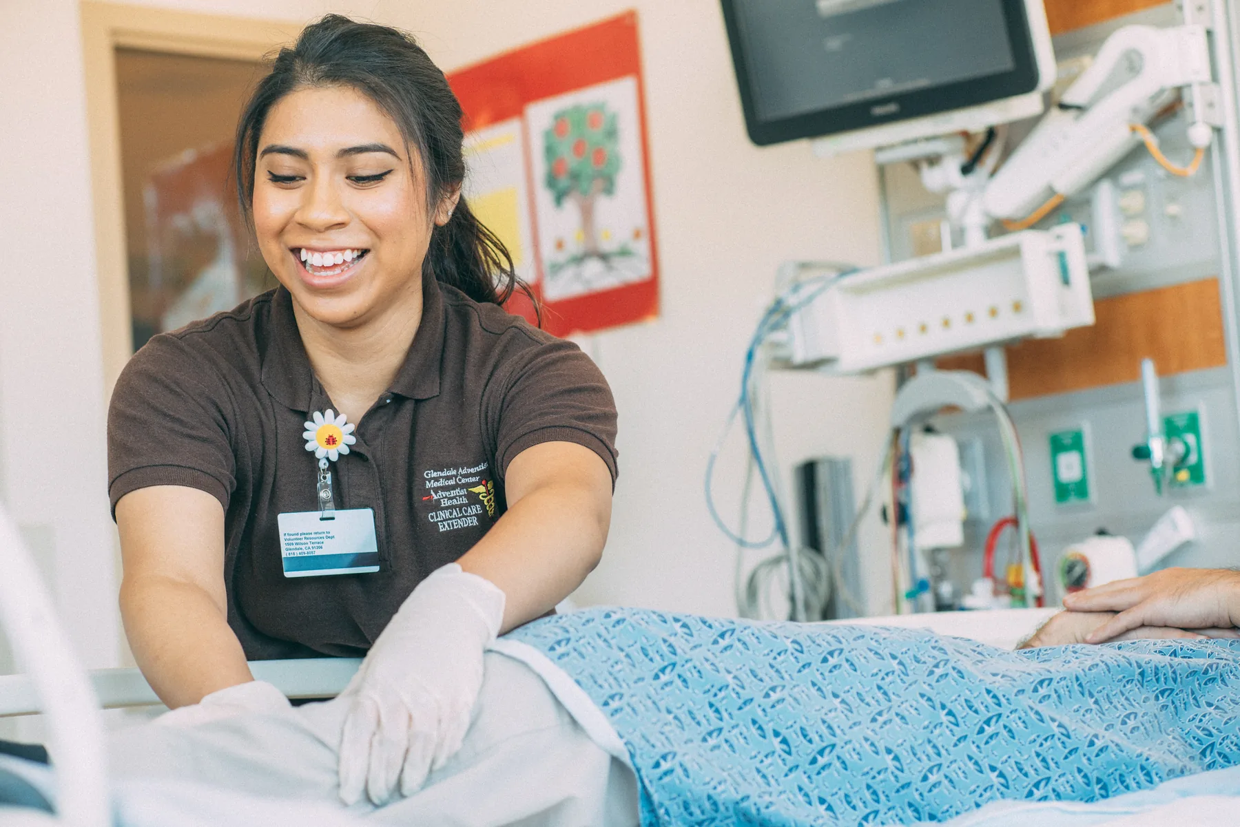A Health Scholar preparing a patient's bed and offering comfort